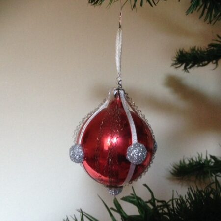 Oude rode kerstbal versierd met band, draad en glitterknopjes