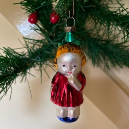 Oude kerstbal van dun geblazen glas een blond meisje in rood, blauw, geel en groen 3e kwart 1900 jaren 1970