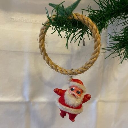 Vrolijke retro kerstman van plastic en chenille aan ring van touw midden 1900