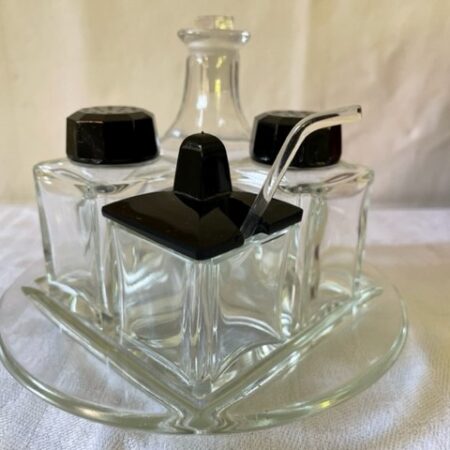 Uit de fifty's een retro 5 delige cruet set met mosterdlepeltje van helder en zwart glas met mosterdlepel van glas op plateau