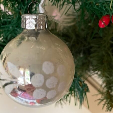 Oude kerstbal van gepatineerd glas in zilver met witte florale decoratie midden 1900