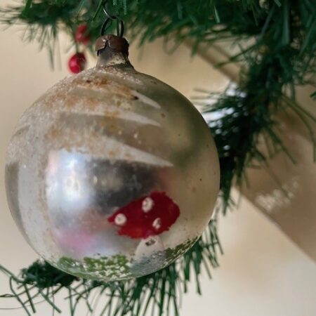 Antieke oude kerstbal van dun geblazen glas in zilver beschilderd met paddenstoelen in het gras in rood, wit en groen 1e kwart 1900