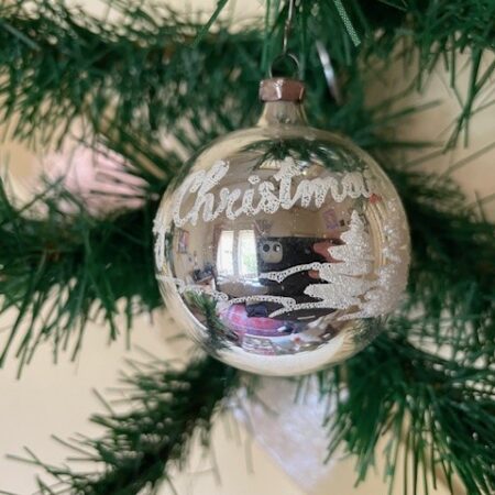 Antieke oude kerstbal van dun geblazen glas met voorstelling en tekst "merry christmas"